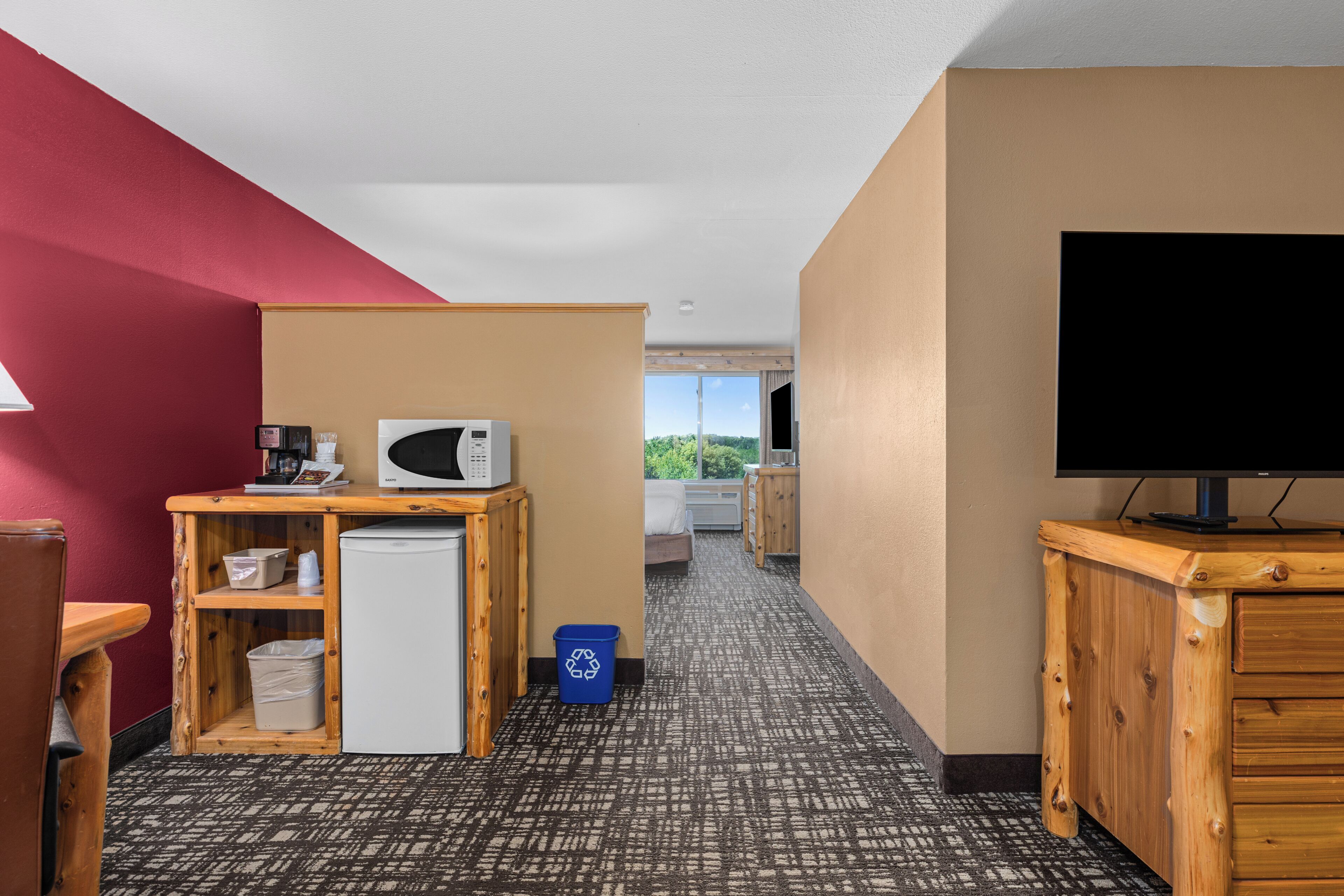 Ein Hotelzimmer mit Küchenzeile, Fernseher, Bett und Blick ins Freie.