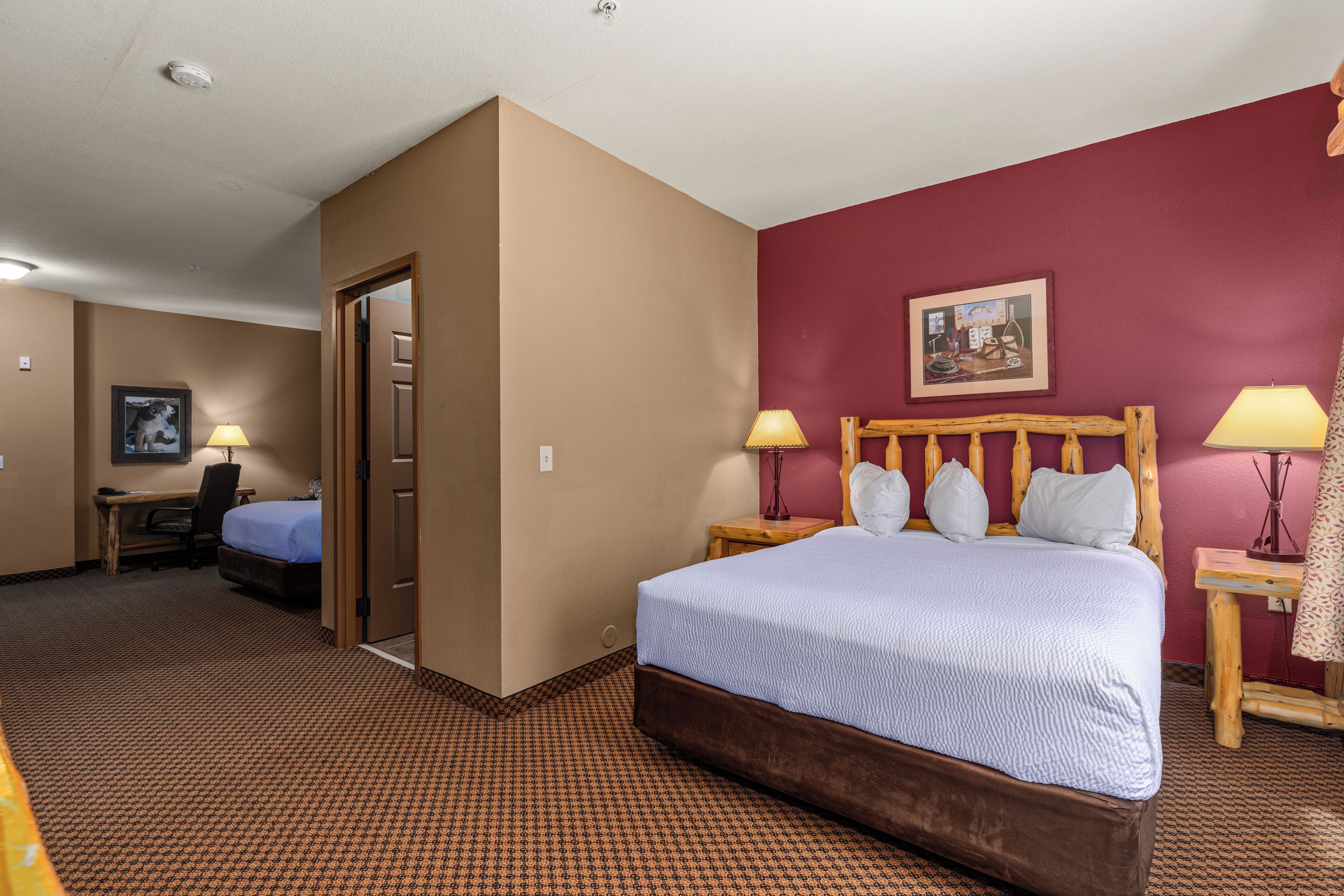 Camera d'albergo con letto, scrivania, sedia e due lampade.