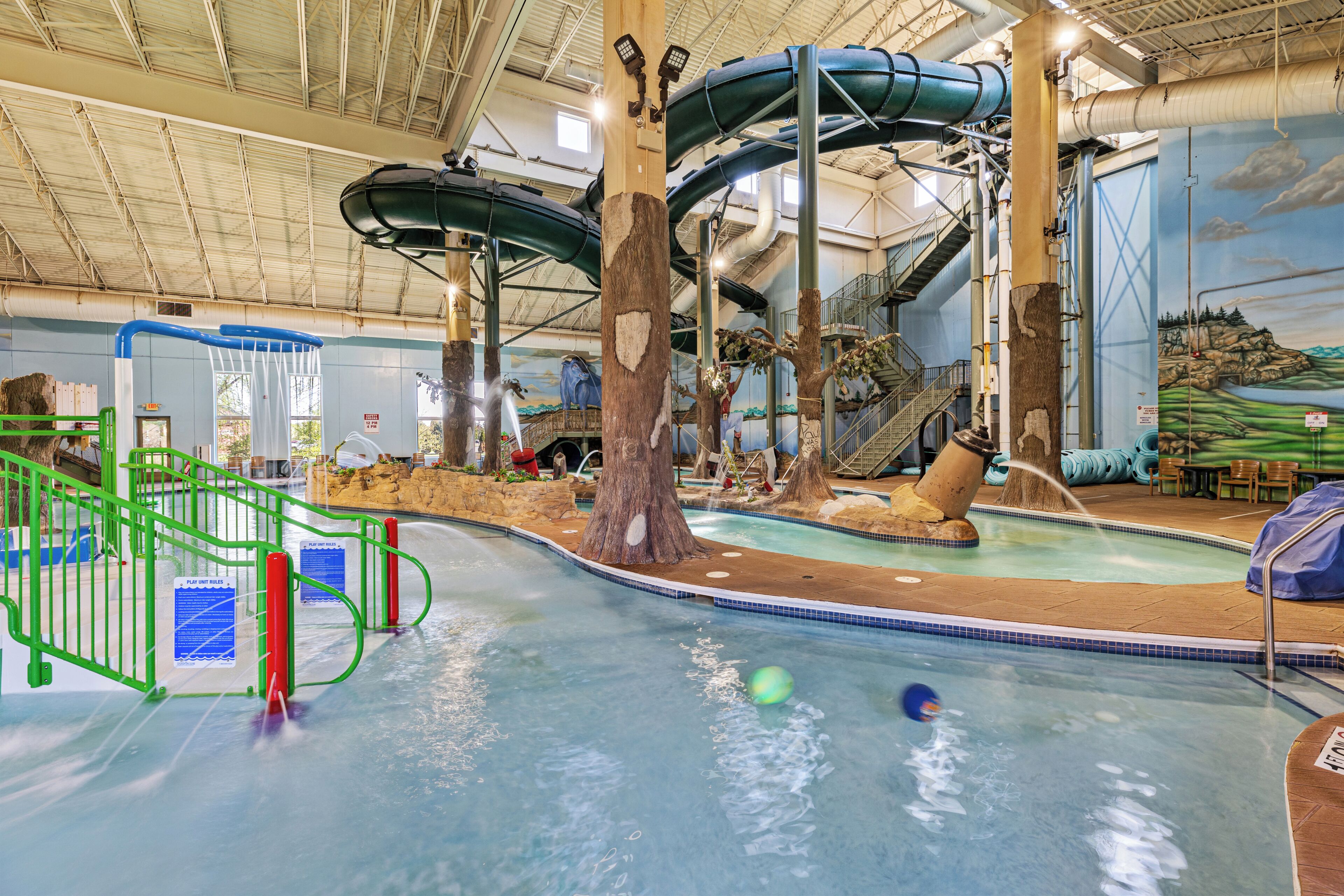 Parque acuático interior con toboganes, piscina y zona de juegos.