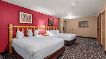 A hotel room with two beds, a red wall, and a patterned carpet.