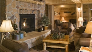 A cozy living room with a stone fireplace, leather sofas, and a coffee table. - The Lodge at Brainerd Lakes, Trademark Collection by Wyndham (Brainerd)