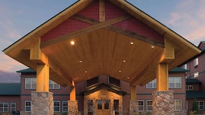 A building with a stone facade, a wooden entrance canopy, and a clear sky. - The Lodge at Brainerd Lakes, Trademark Collection by Wyndham (Brainerd)