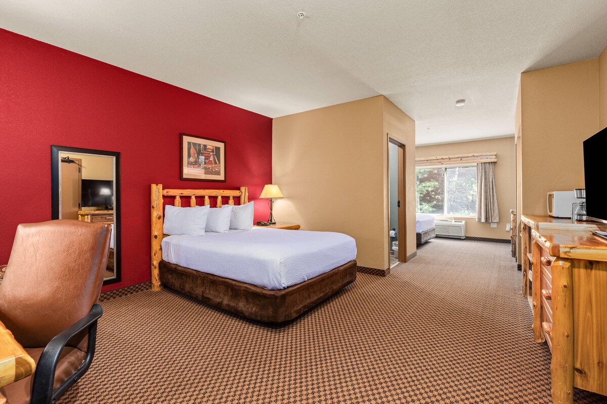 A hotel room with a bed, a desk, a chair, a mirror, and a window.