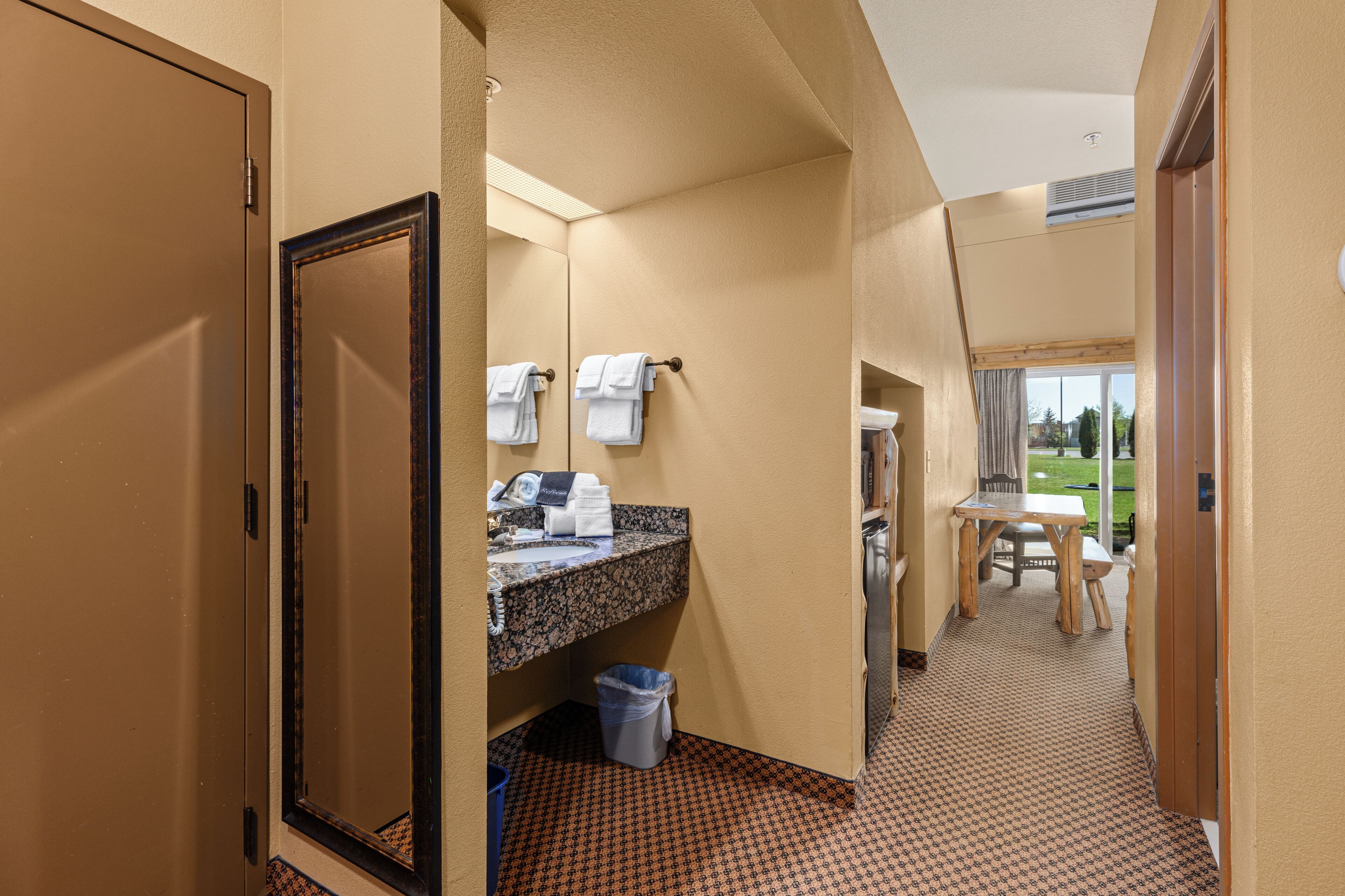 A hotel bathroom with a sink, mirror, and towel rack.