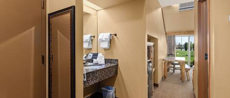 A hotel bathroom with a sink, mirror, and towel rack.