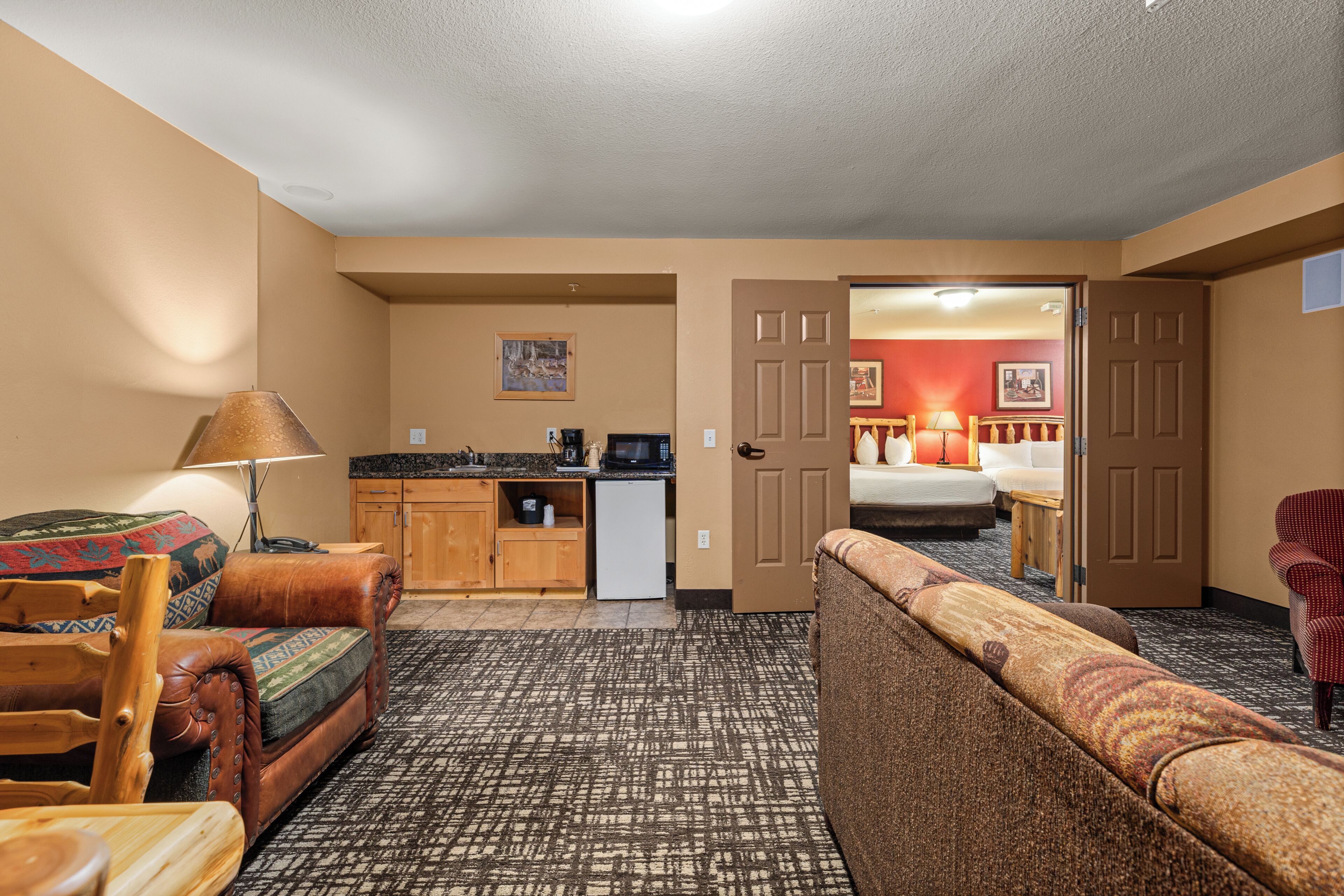 A hotel room with a kitchenette, a sofa, a chair, and a bed.