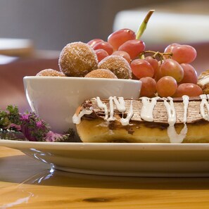 A dessert plate with a pastry topped with white icing, a bowl of fruit, and sugar-coated round sweets. - The Lodge at Brainerd Lakes, Trademark Collection by Wyndham (Brainerd)