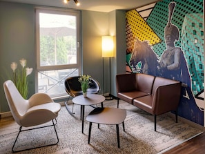 A modern room with a large window, a mural, and a seating area with two chairs and a table. - B&B Hotel Hannover-Lahe (Hannover)