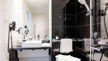 A modern bathroom with a glass shower enclosure, a white sink, and a handheld hair dryer.