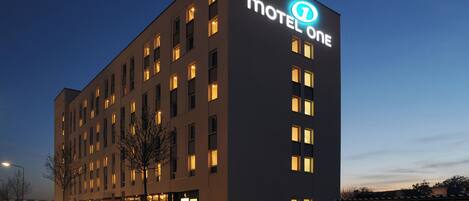 A modern motel building with a prominent sign, multiple windows, and a flat roof.