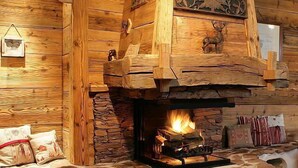 Una habitación acogedora con chimenea de piedra, paredes de madera y una cama con almohadas.