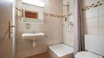 Ein Badezimmer mit Waschbecken, Spiegel, Dusche und Toilette.