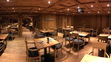 Ein Restaurant mit Holzvertäfelung, mehreren Tischen und Stühlen.