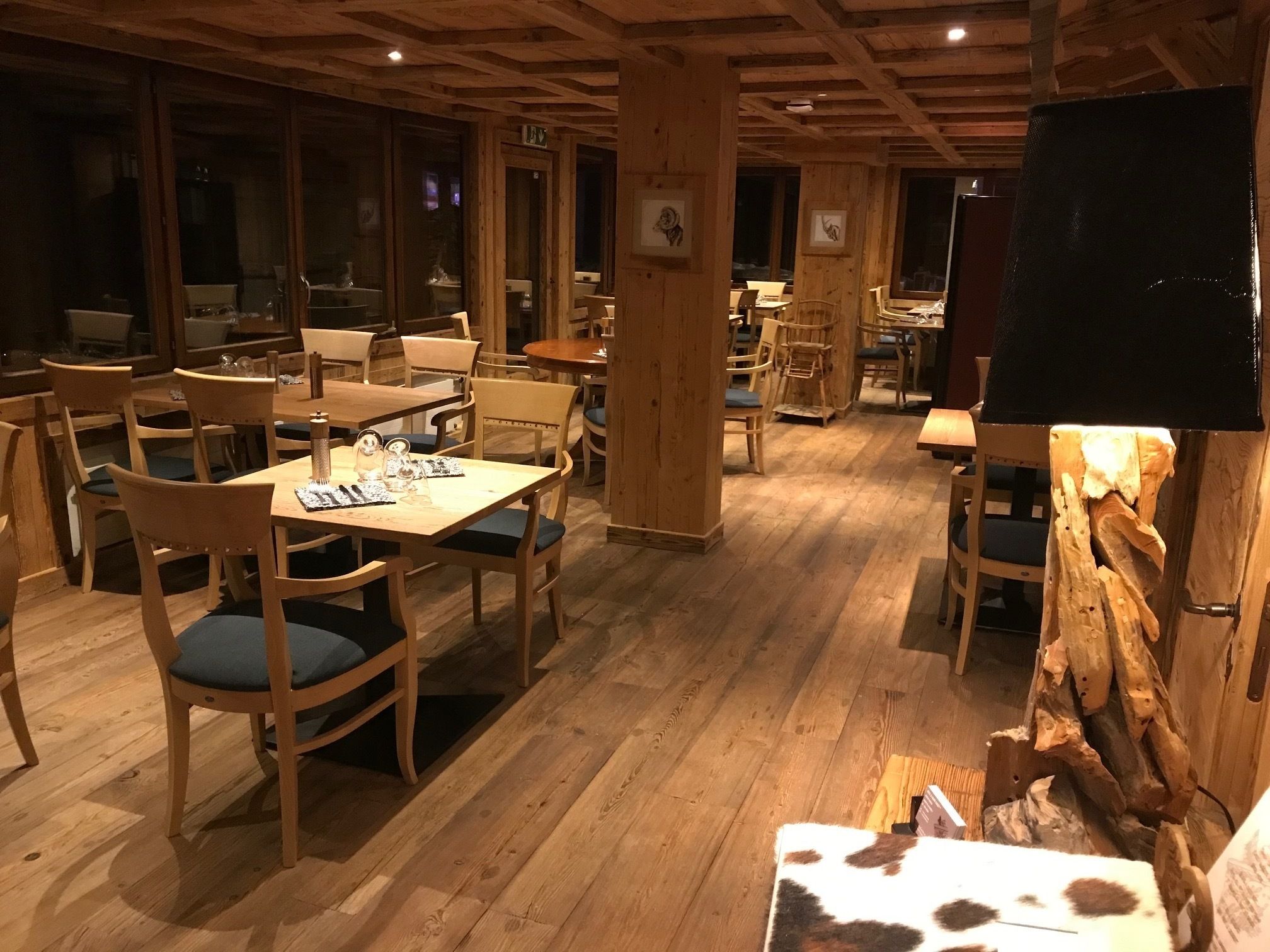 Ein gemütliches Restaurant mit Holztischen und -stühlen, einer Holzbalkendecke und rustikalem Dekor.