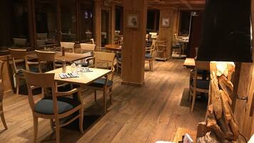 Ein gemütliches Restaurant mit Holztischen und -stühlen, einer Holzbalkendecke und rustikalem Dekor.