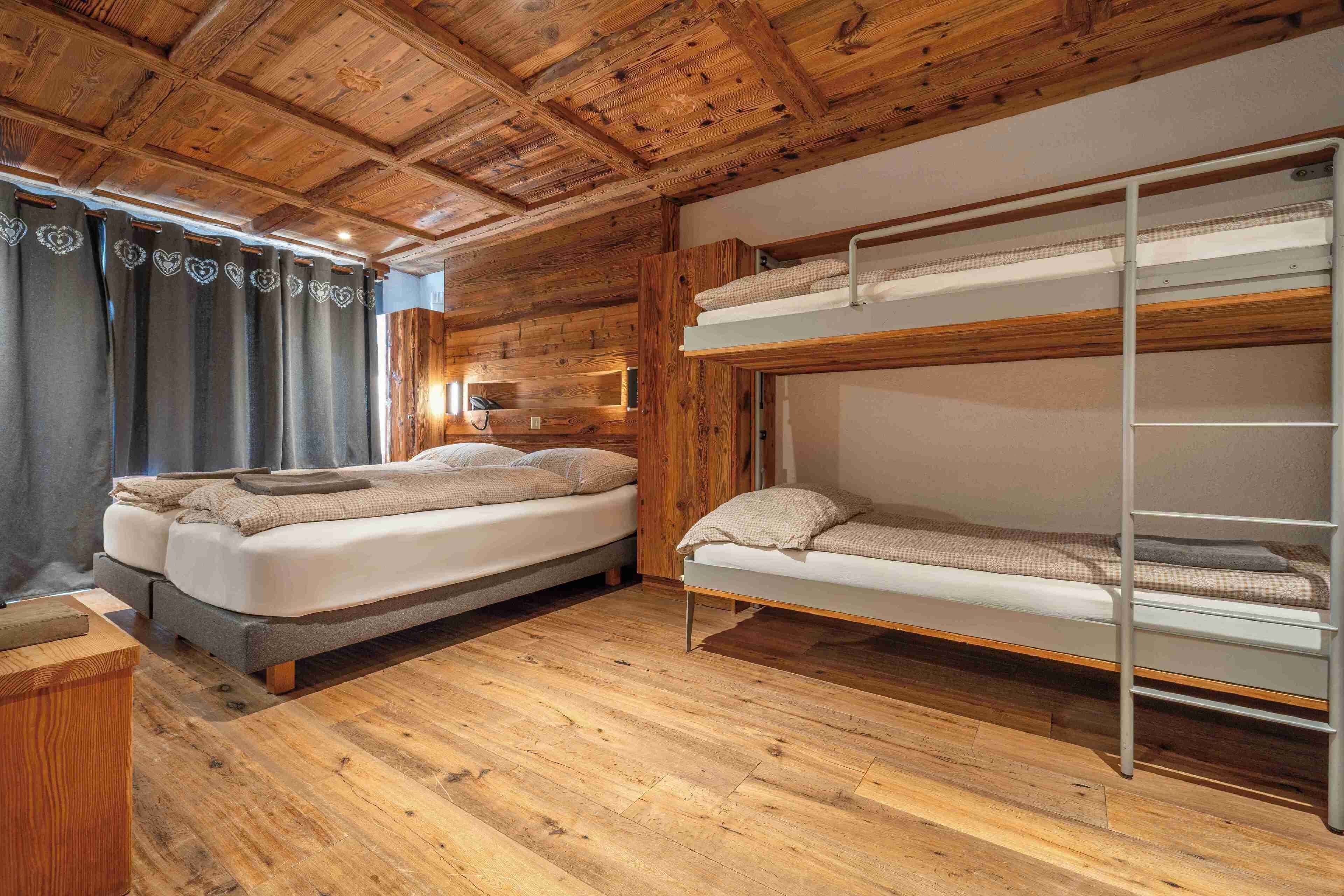 Une chambre avec deux lits superposés, un plancher en bois et un plafond en bois.