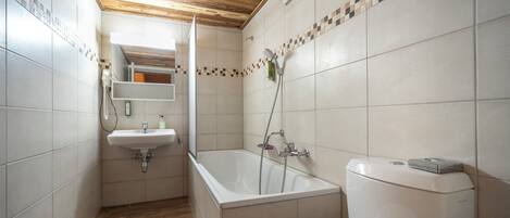 A modern bathroom with a wooden ceiling, a bathtub, a toilet, and a sink.