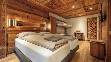 A wooden cabin bedroom with bunk beds, a small table, and a wall-mounted shelf.