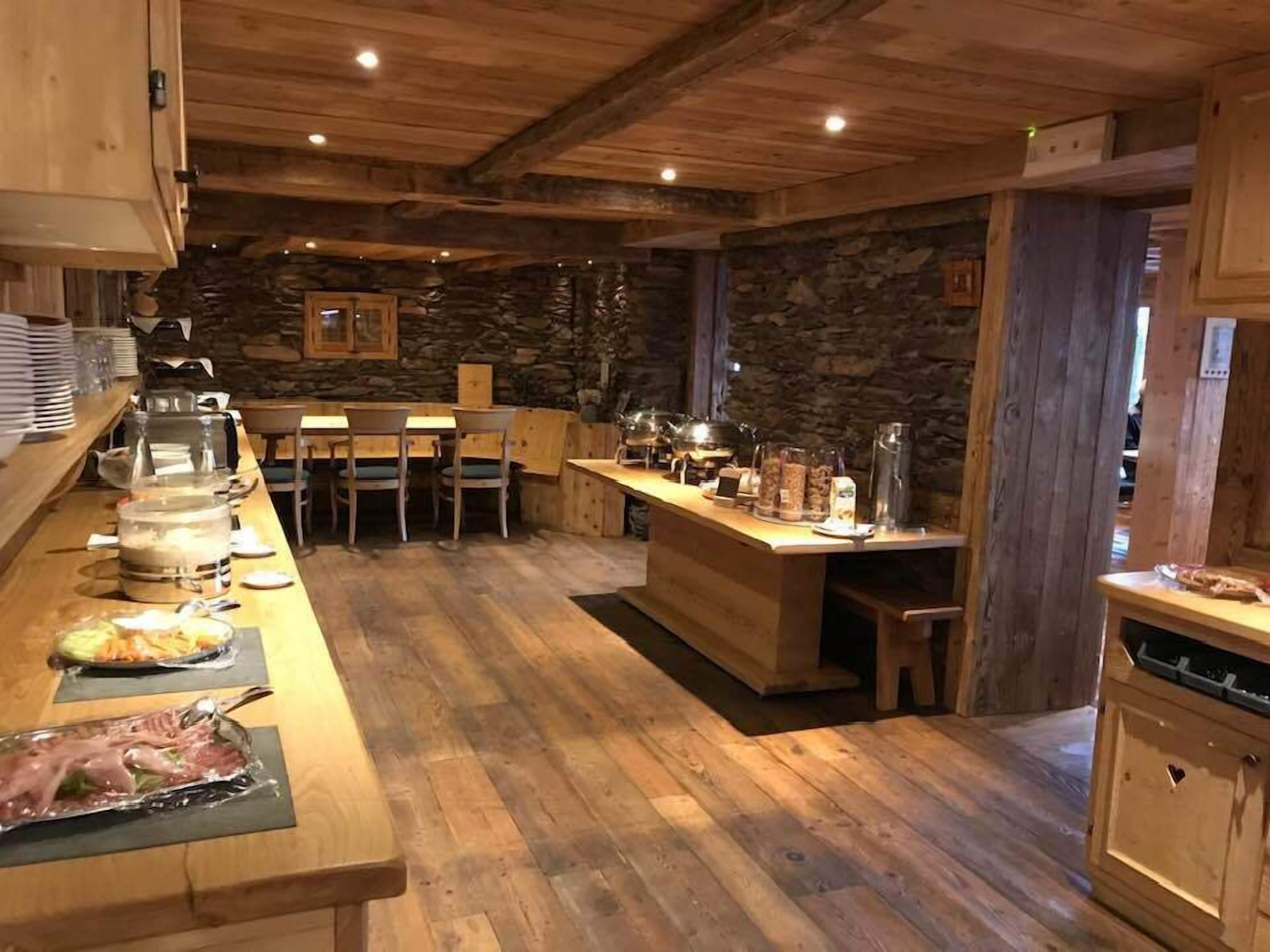 A rustic wooden interior with a long counter, stone walls, and wooden ceiling beams.