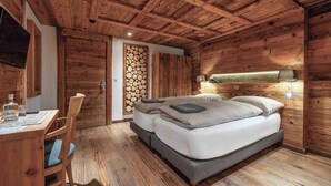Un dormitorio con techo de madera, una cama con almohadas, una mesita de noche con vasos y una lámpara de pared.