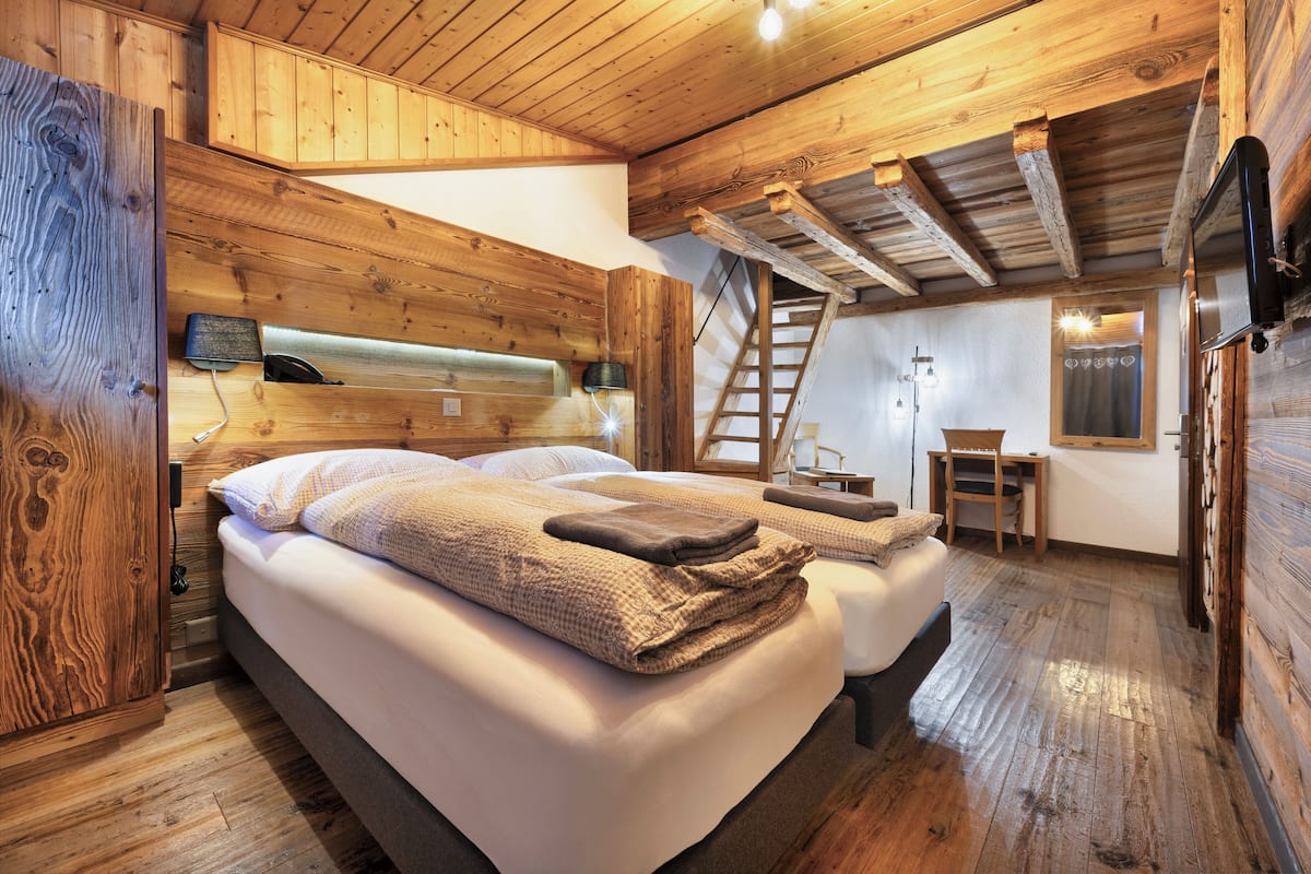 Un dormitorio de estilo cabaña de madera con una cama grande, un escritorio y una silla.
