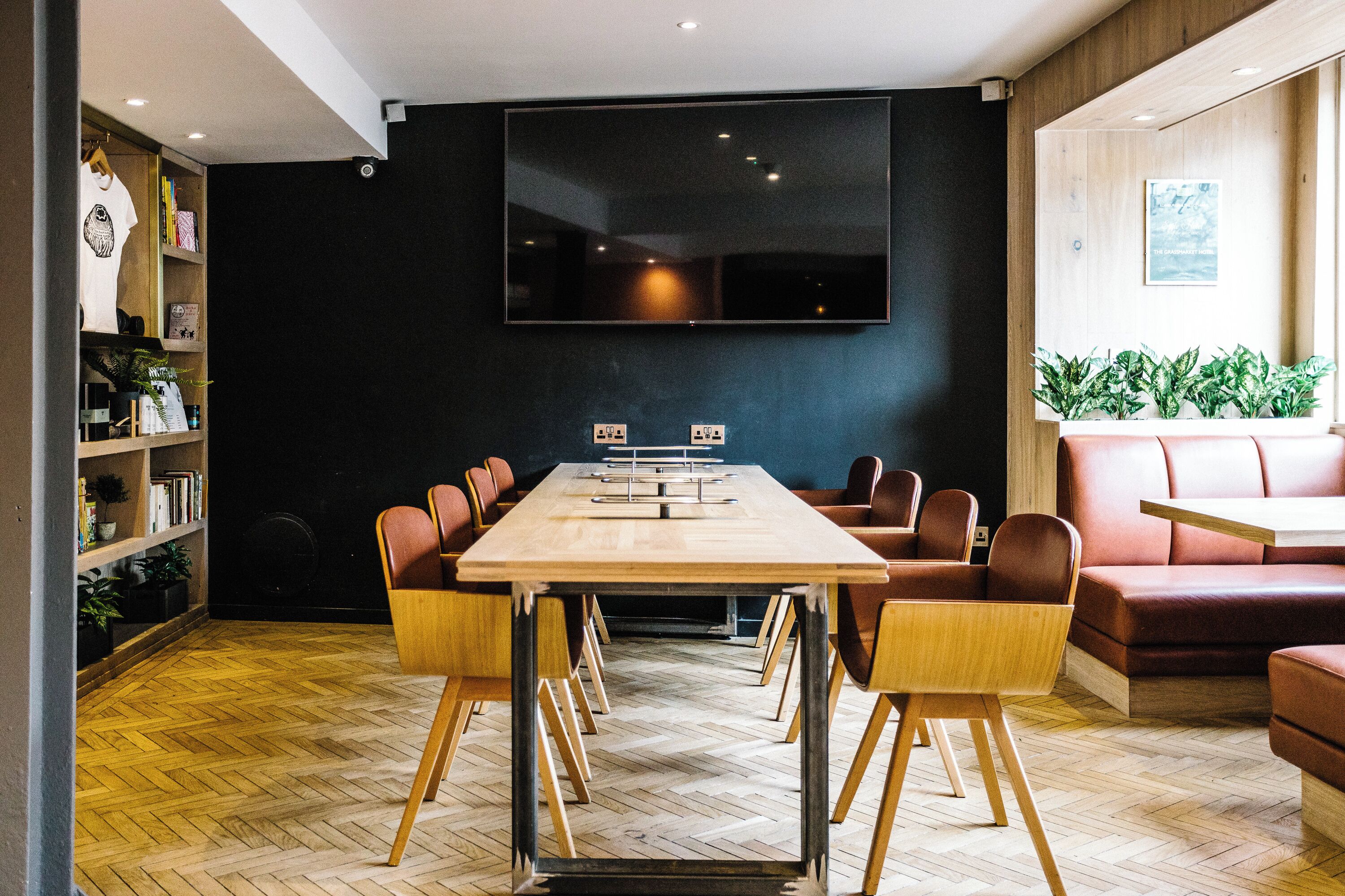 Ein Konferenzraum mit langem Tisch, Stühlen, einer Couch und einem Fernseher an der Wand.