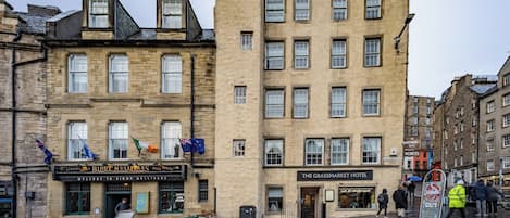 A historic building with multiple stories, a pub named 'Biddy Mulligans' on the ground floor, and 'The Grassmarket Hotel' across the street.