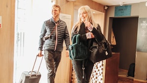 A man and a woman walking inside a hotel lobby with a wooden floor and a reception desk. - Grassmarket hotel (Edinburgh)