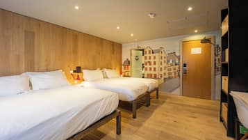 A hotel room with two beds, wooden flooring, a mural of buildings, a door, and a bookshelf.