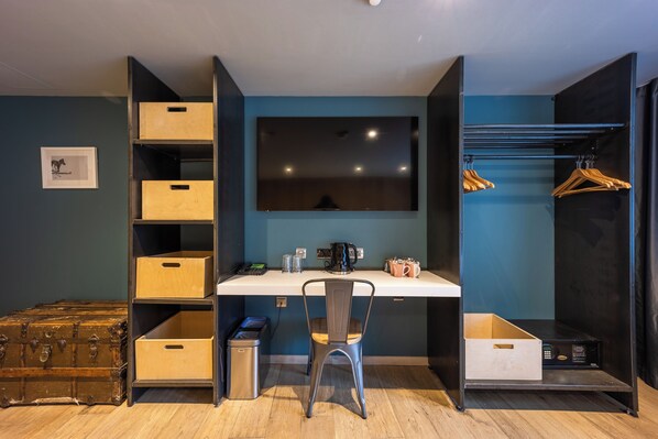 Habitación pequeña con escritorio, silla, armario y almacenaje.