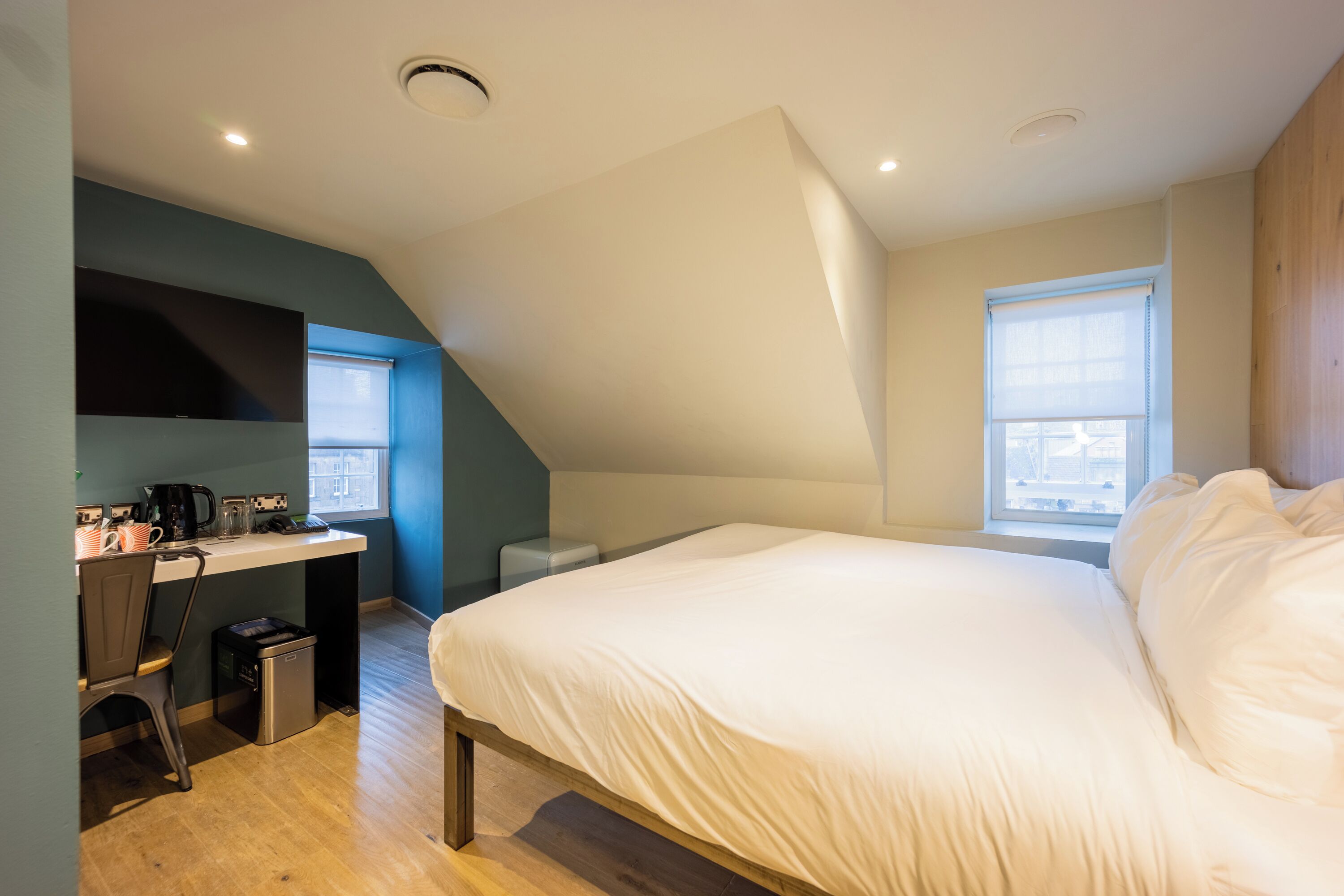 A bedroom with a bed, a desk, and a window.