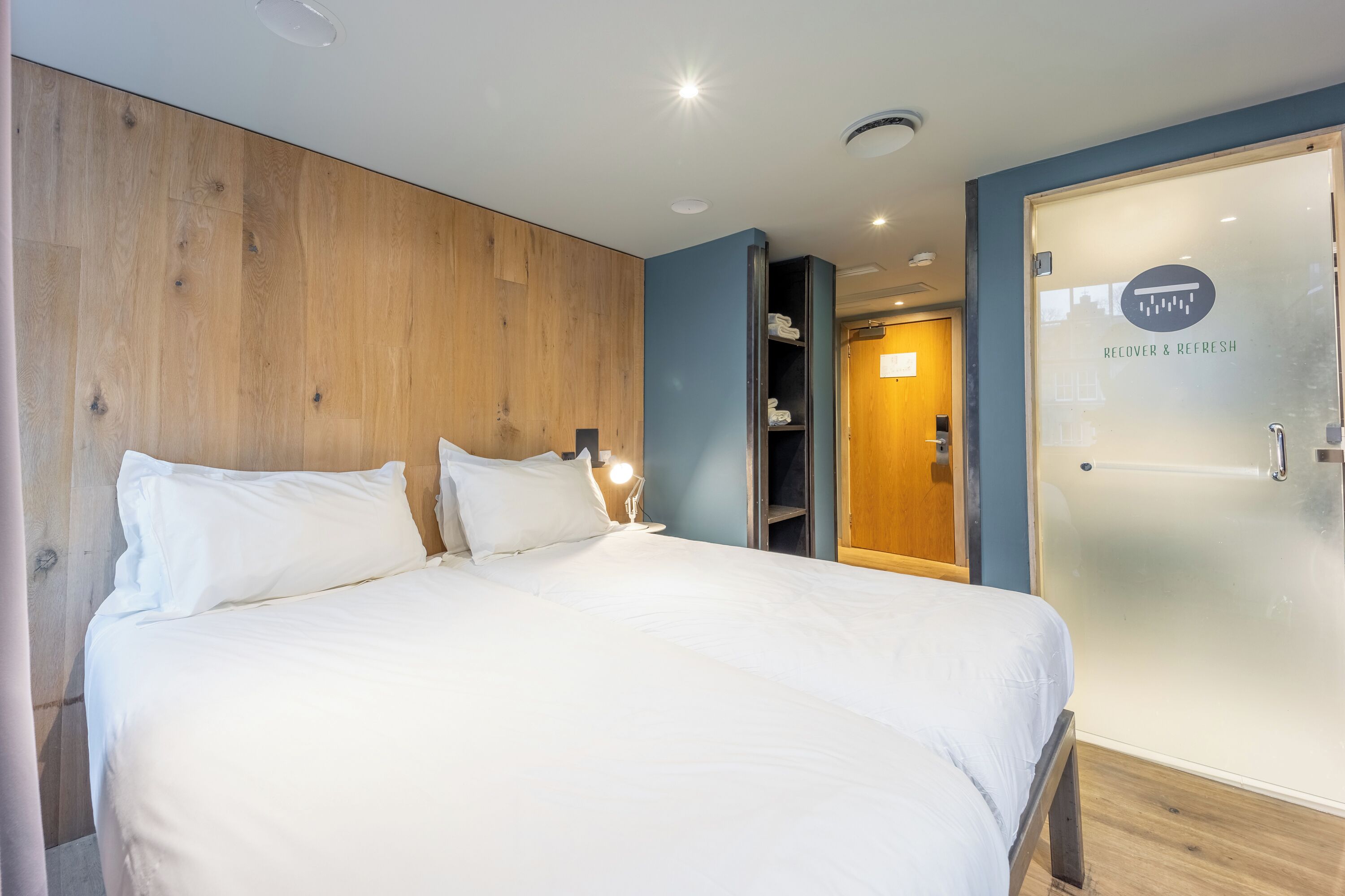 Una habitación de hotel con una cama, un armario y una puerta con panel de vidrio esmerilado.