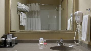 Baño de hotel con lavamanos, espejo, toallero y secador de pelo.