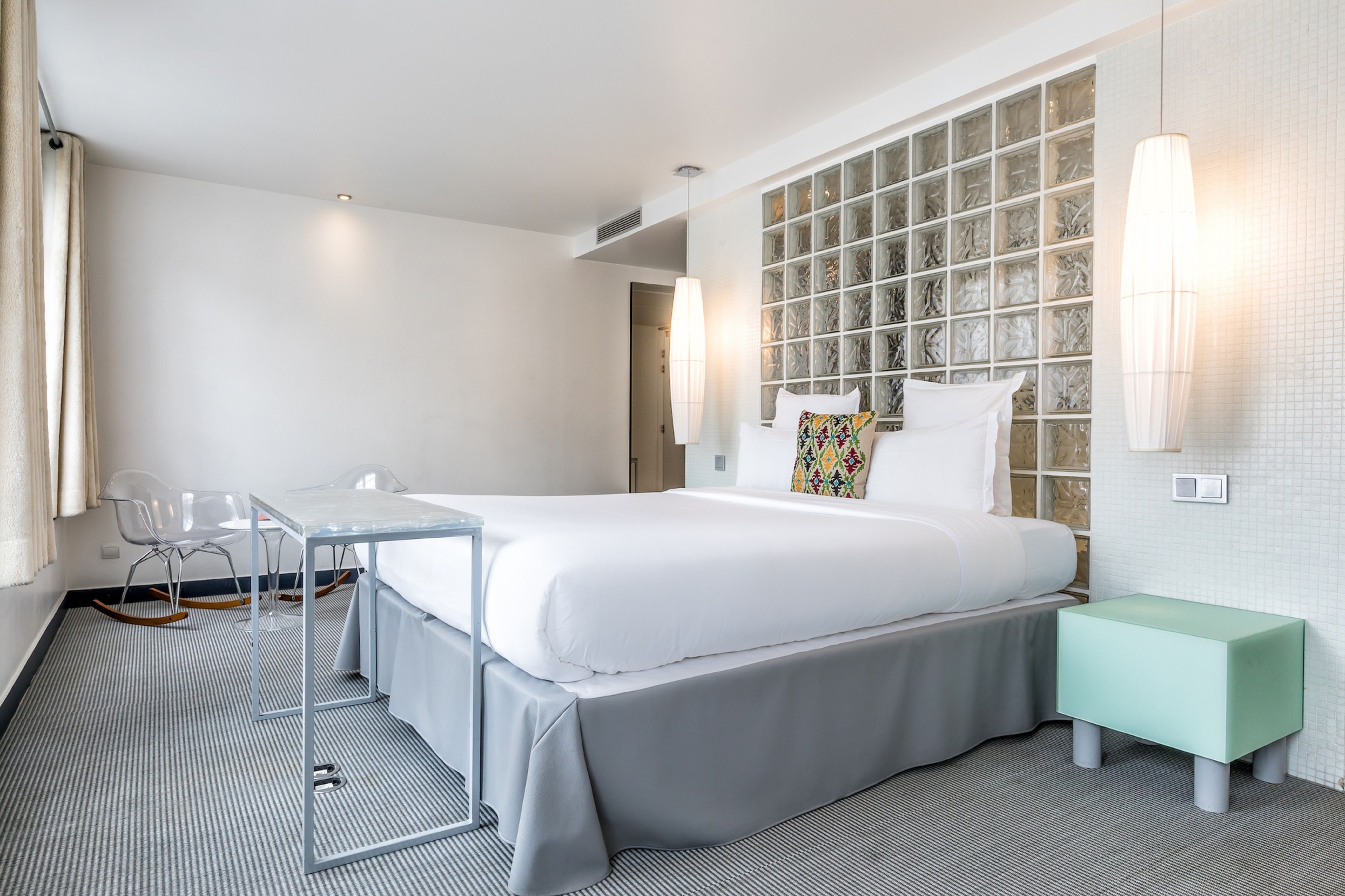 A hotel room with a large bed, a desk, a chair, and a small table.