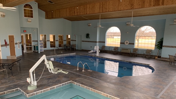 En inomhuspool med en hoppställning, flera sittgrupper och stora fönster.