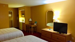 Ett hotellrum med två sängar, ett skrivbord med en stol, en tv på en byrå och en spegel på väggen.