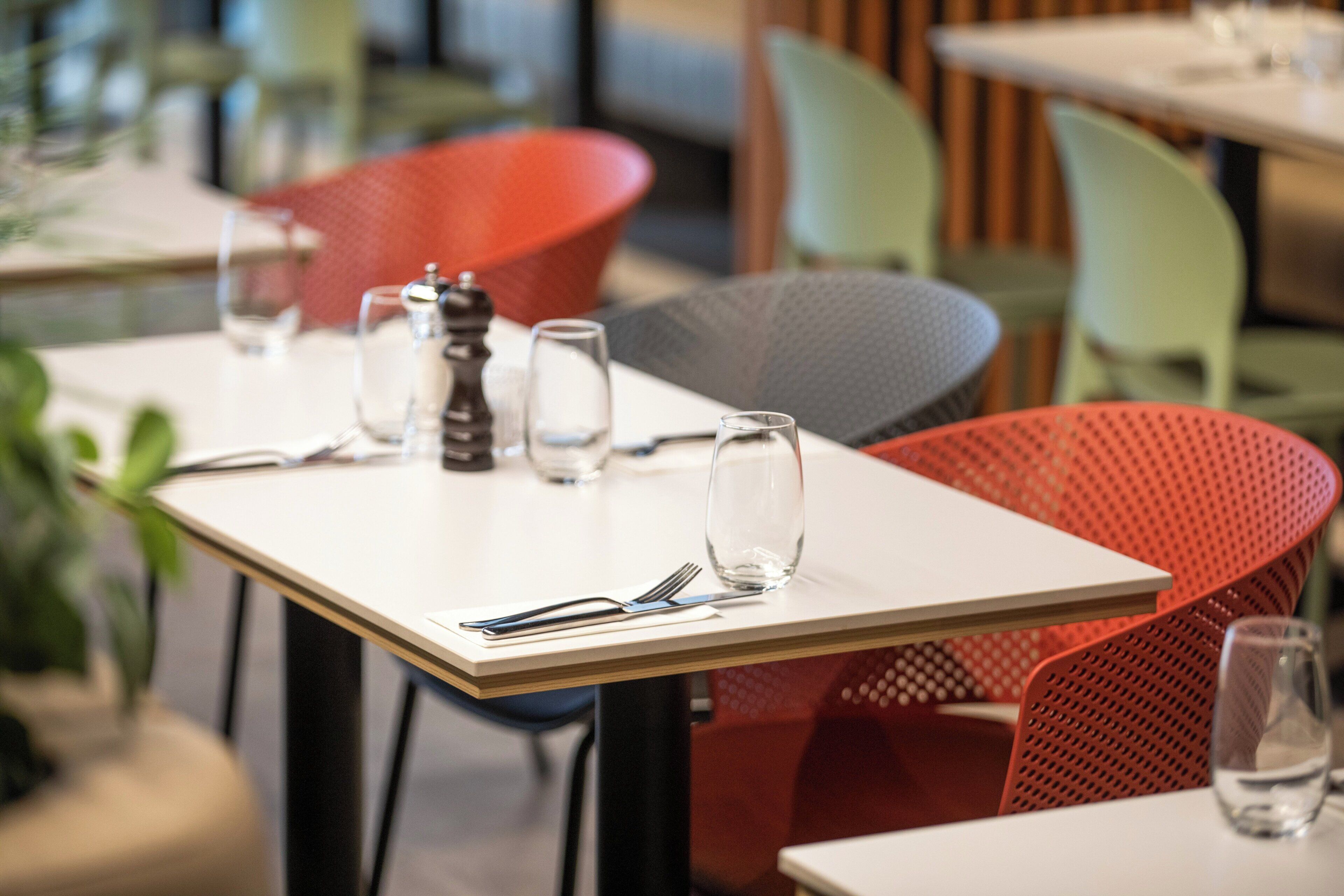 A dining area with tables set for two, featuring modern chairs and a minimalist table design.