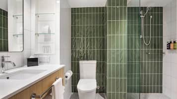 A modern bathroom with a glass-enclosed shower, a white sink, and a toilet.