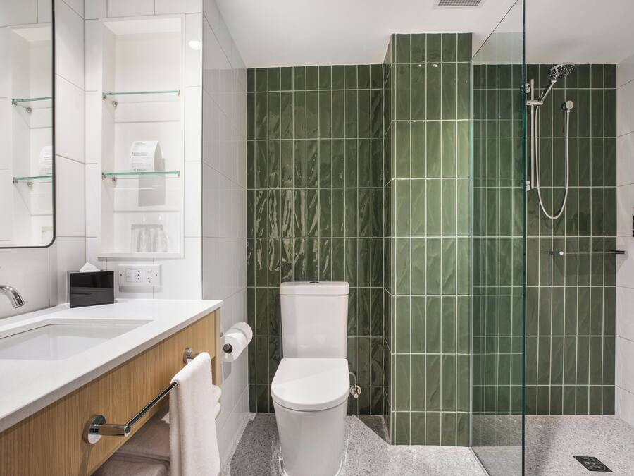 A modern bathroom with a glass-enclosed shower, a white sink, and a toilet.