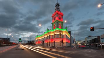 Un bâtiment historique doté d’une tour horloge, entouré de lampadaires et de feux de signalisation modernes.
