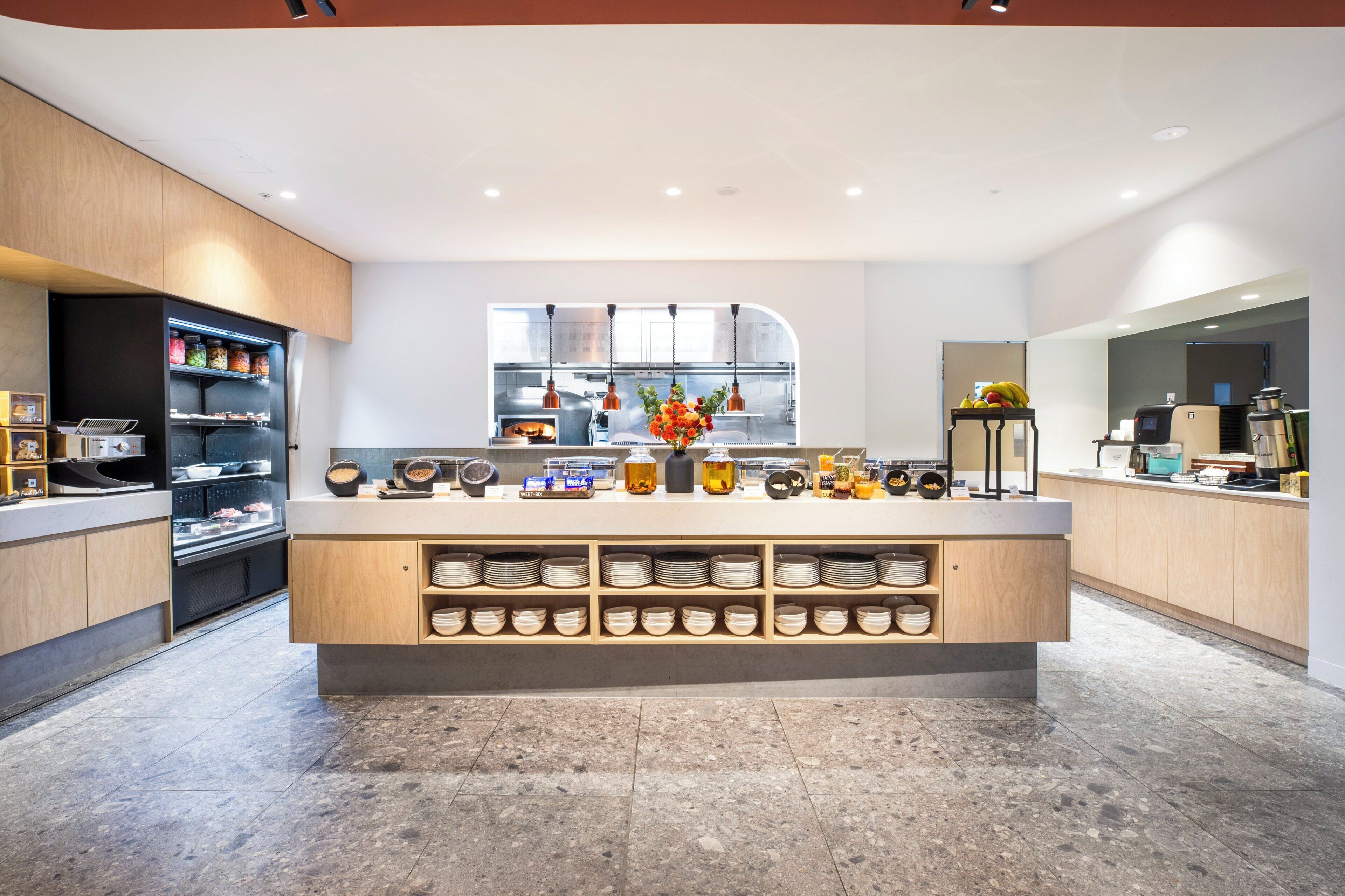 A modern kitchen with a central island, wooden cabinets, and a variety of kitchen appliances.