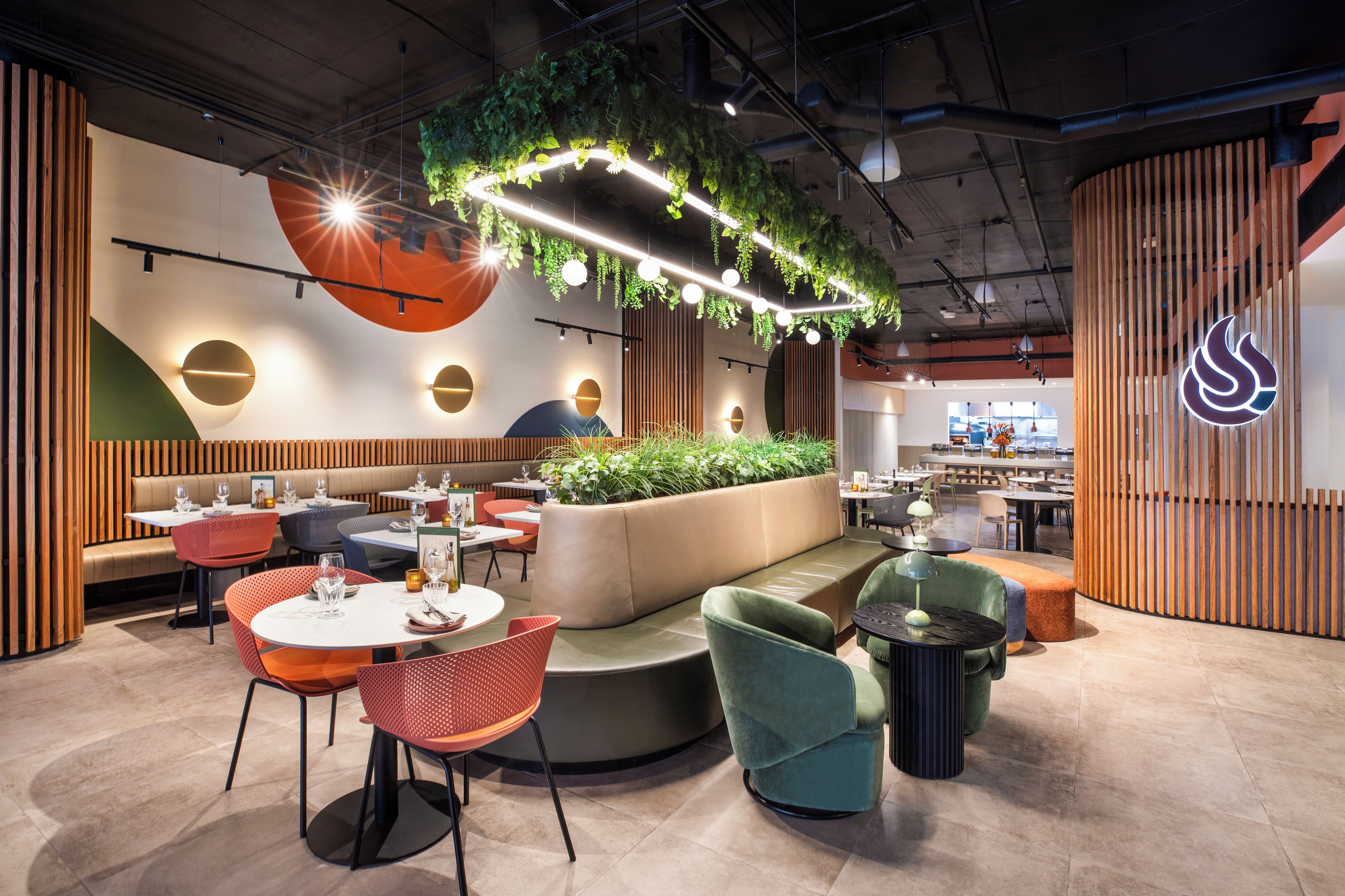 Un interior de restaurante moderno con cabinas, mesas redondas y plantas colgantes.
