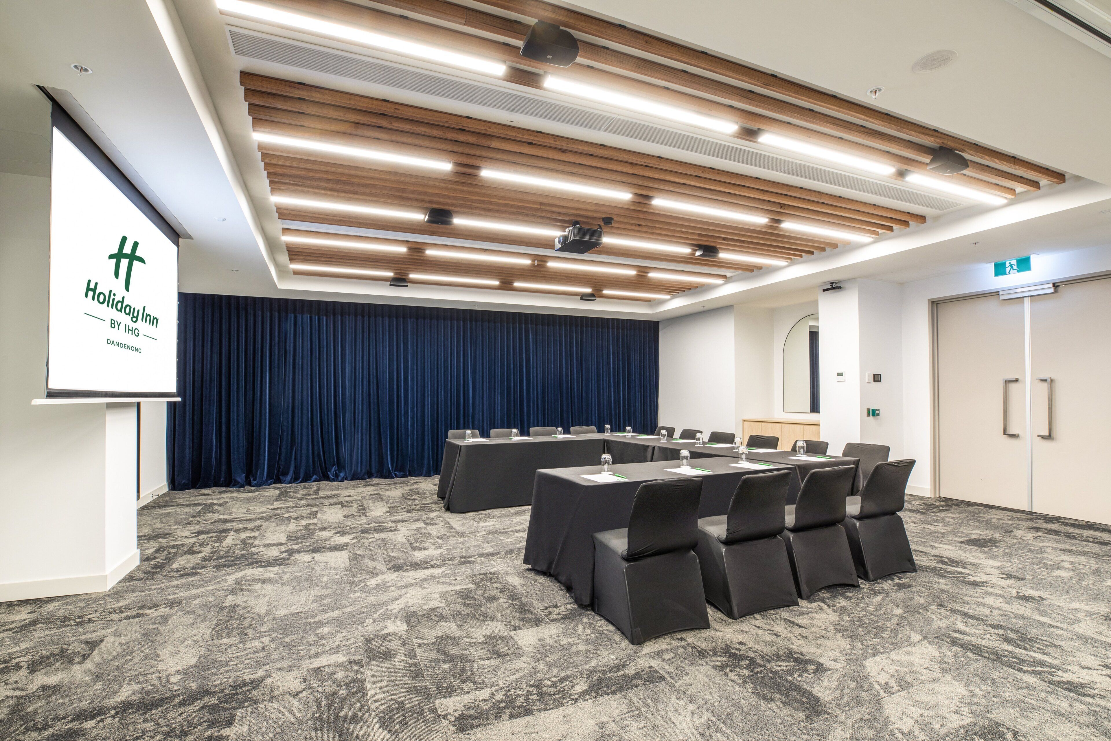 A conference room with a long table, chairs, a podium, and a blue curtain backdrop.