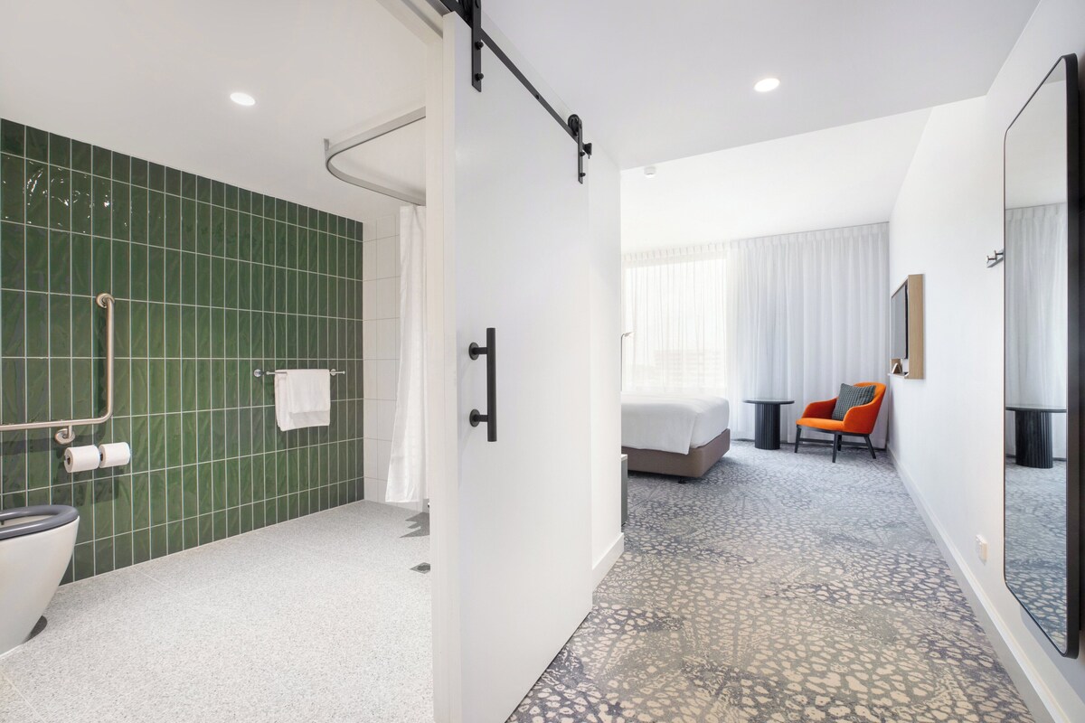 Habitación de hotel moderna con ducha, inodoro y cama.