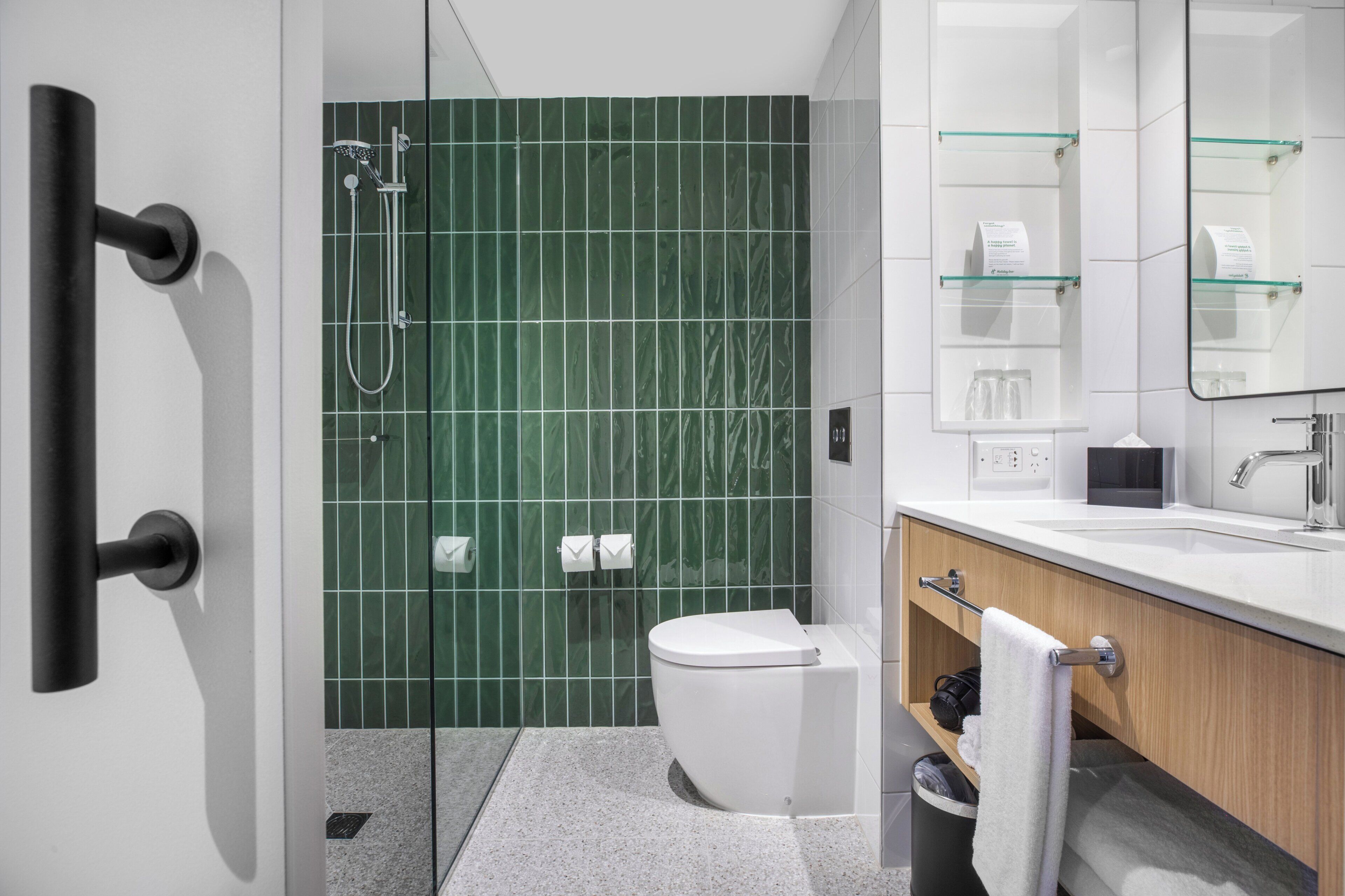 A modern bathroom with a glass shower enclosure, a white toilet, a sink with a mirror, and a towel rack.