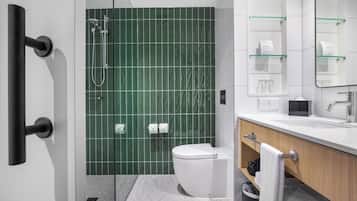 A modern bathroom with a glass shower enclosure, a white toilet, a sink with a mirror, and a towel rack.