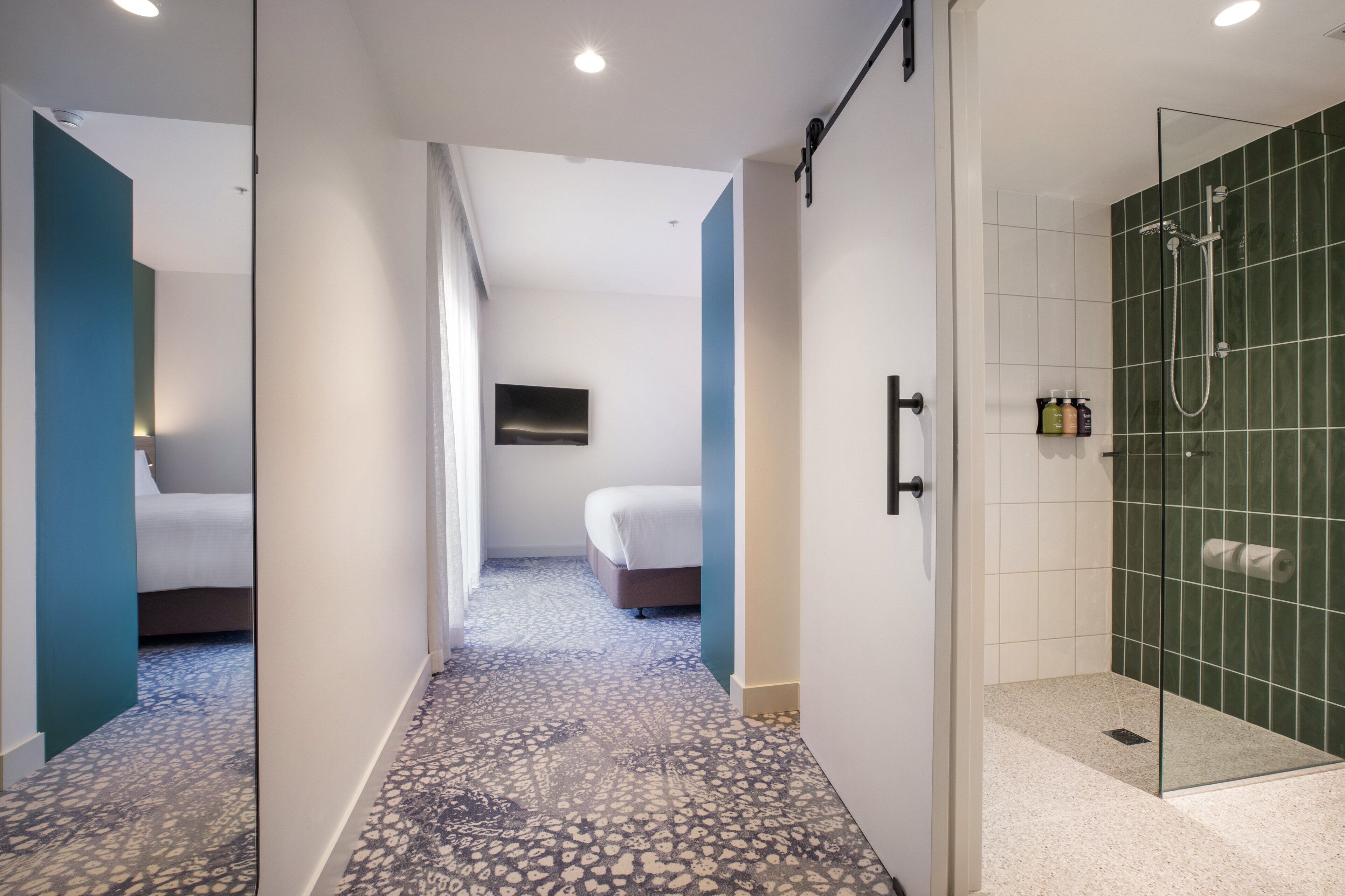 A hotel room with a shower, a bed, and a TV.