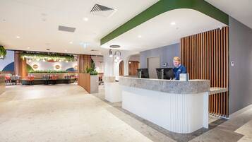 A reception area with a counter, seating area, and a person behind the counter.