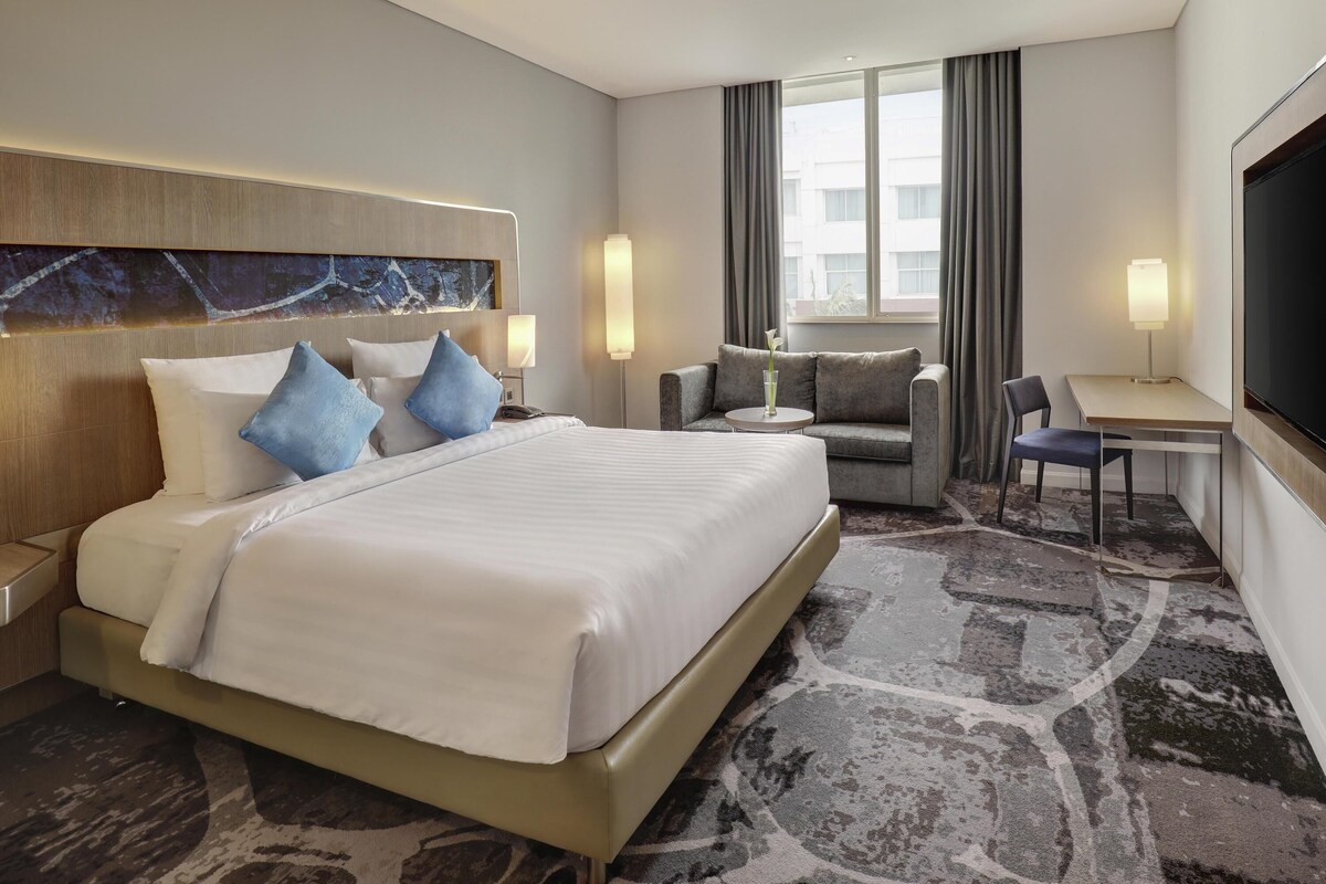 Ein Hotelzimmer mit einem großen Bett, einer Sitzecke, einem Schreibtisch und einem Fernseher.