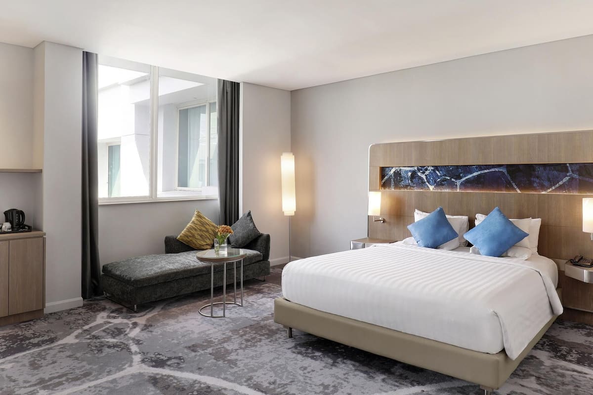 Ein Hotelzimmer mit einem Bett, einem Sofa, einem kleinen Tisch und einem Nachttisch.